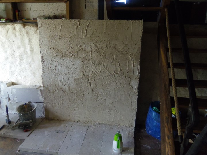 le "mur" en béton cellulaire contre lequel le foyer prendra place.
Il est enduit en plâtre/sable pour donner le relief nécessaire à l'enduit terre qui viendra.